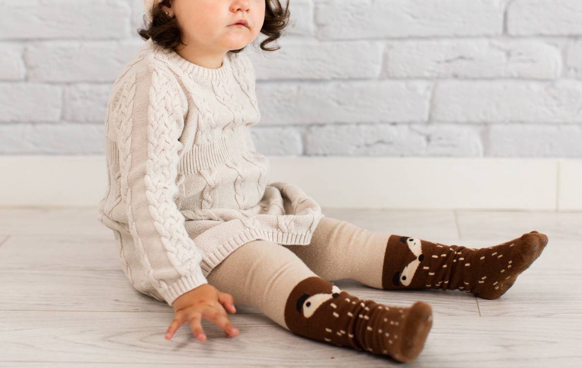 کودکی با جوراب قهوه‌ای نشسته است.-نهایت خرید